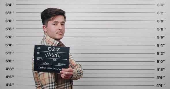 Side Profile Mugshot of Male Arrested Looking to Camera While Standing in Front of Police Metric