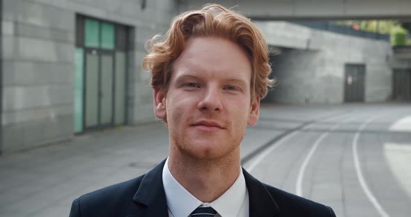 Confident Young Redhead Businessman Looks at the Camera and Smile While Standing in the Business