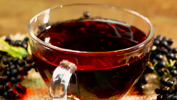 Close Up Natural Red Berry Tea In A Glass Cup On A Turntable. Berry Tea From Black Elderberry.