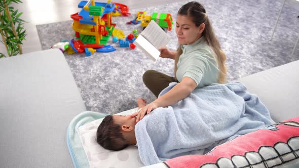 Mother reading a book and her sleeping baby.