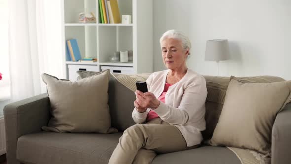 Senior Woman with Smartphone Messaging at Home 