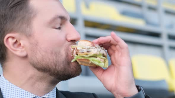 Young Hungry Businessman Eating Hamburger