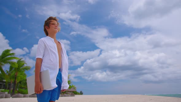 A Student is Engaged in Selfeducation Sitting on the Beach Against the Background of the Turquoise