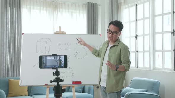 Asian Male Teacher With Glasses Shoots Video By Smartphone Camera While Teaching Math At Home