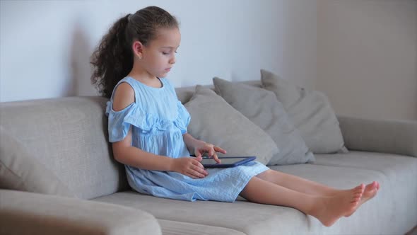Happy Little Girl or Child Playing at Home Relaxing Use a Smartphone Cuddling Sit on Sofa Daughter
