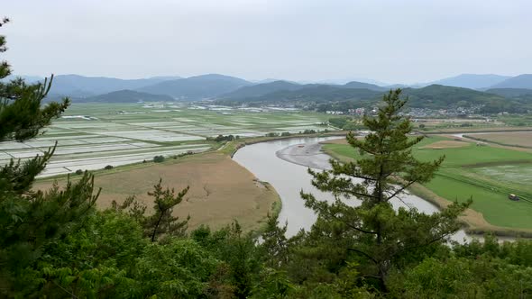 Aerial wide shot over Yongsan Observatory with river, flooded rice fields and bay reed field in Sout