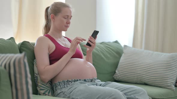 Pregnant Woman Using Smartphone on Sofa