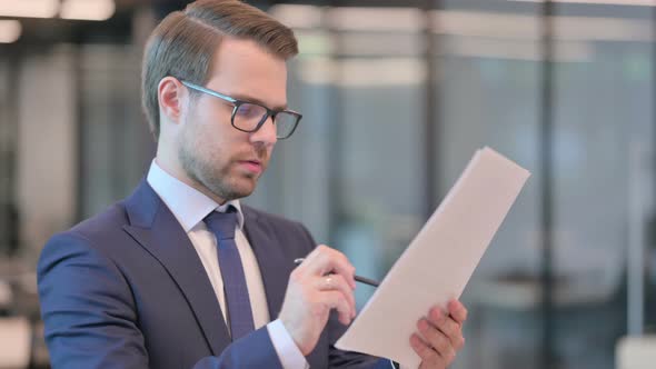 Portrait of Businessman Reading Documents in Office