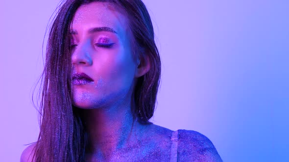 Beautiful Woman with Sparkles on Her Face in Ultraviolet Light