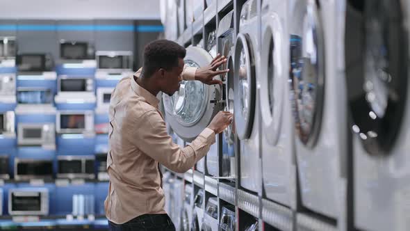 Single Afroamerican Man is Choosing Washing Machine in Home Appliances Store Man is Viewing