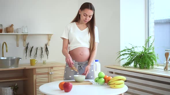Pregnant Woman Make Granola for Breakfast Pour Flake Oatmeal Cereal in Plate on Kitchen Spbd