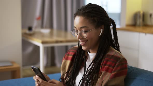 Young Woman Using Smartphone at Home on a Couch Side View