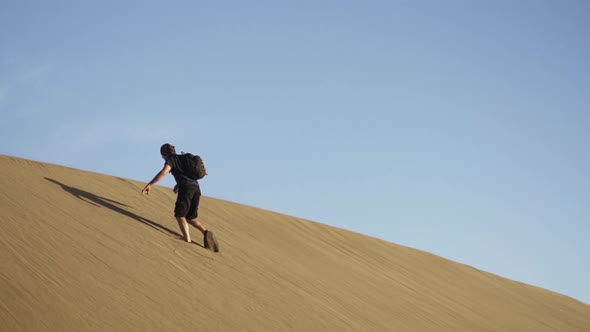 Man Walking To Top Of Steep Sand Dune