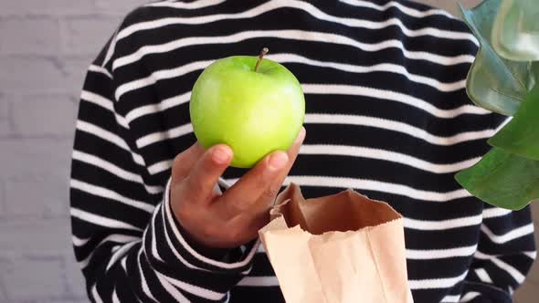 Hand Holding Green Apple and Holding a Paper Shopping Bag