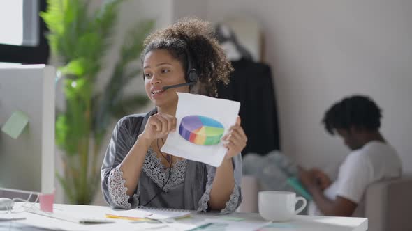 Confident Charming Smiling Woman in Earphones and Nightie Pointing at Graph Convincing in Virtual