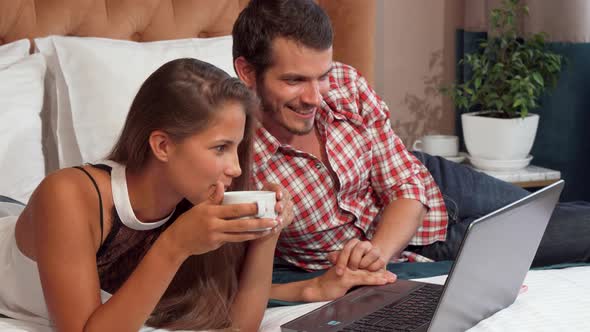 Lovely Couple Using Laptop at Their Hotel Room, While Having Coffee