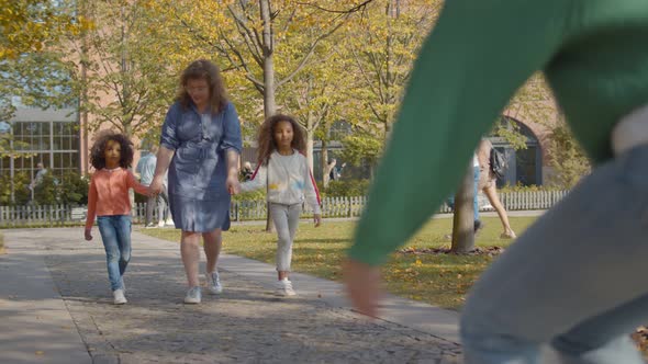 Caucasian Babysitter with Two African Girls Walking in Autumn Park