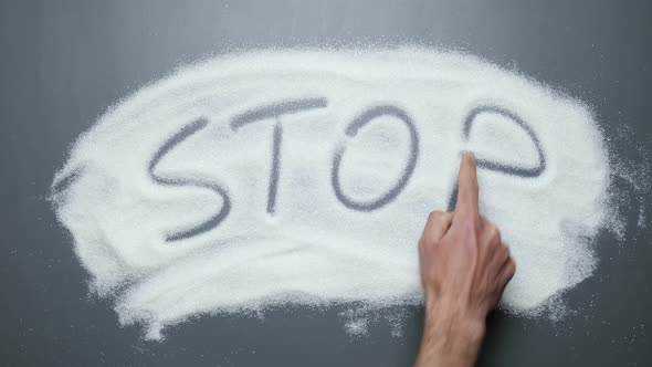 Hand writes word stop on sugar. Stop diabetes. Cancer and obesity diseases.