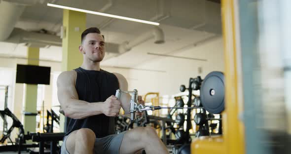 Young Muscular Athlete Works Out in a Modern Gym on Seated Row Machine