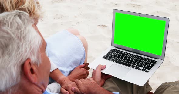 Senior couple using laptop at the beach