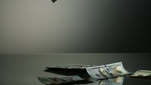 American $100 Bills Falling onto a Reflective Surface