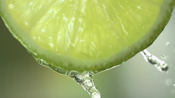 Slow Motion Macro Shot of Flowing Lime Juice From Lime Slice