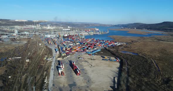 4K Aerial drone view of port container terminal. Industrial cargo harbor with ships and cranes.