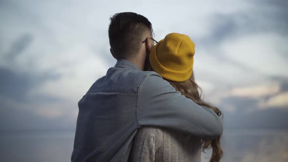 Back View of Loving Boyfriend Hugging Girlfriend on River Bank in Dusk