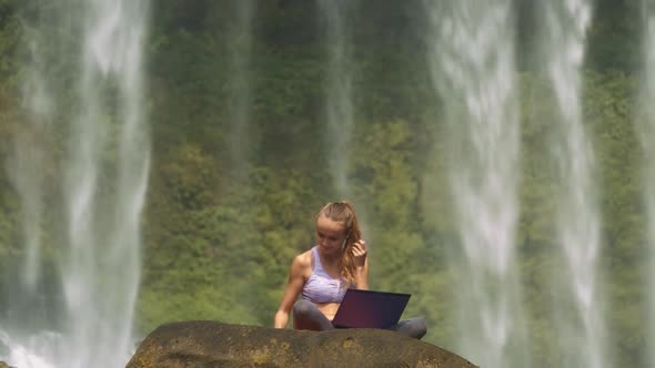 Girl Starts Working on Laptop By Waterfall Streams