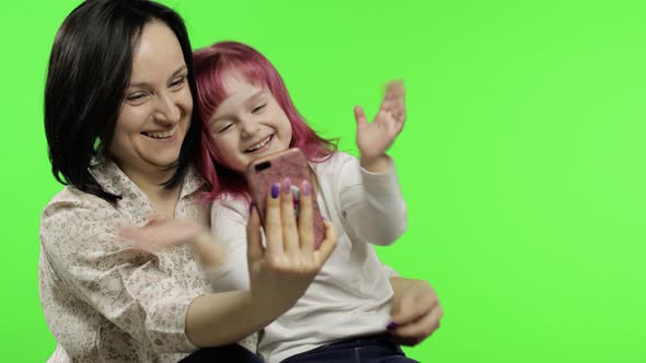 Mother, Daughter Holding, Using Smart Phone Talking on Video Call. Social Media