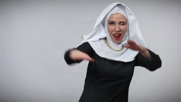 Joyful Carefree Woman in Nun Costume Having Fun at Grey Background Stretching Hands Aside Smiling