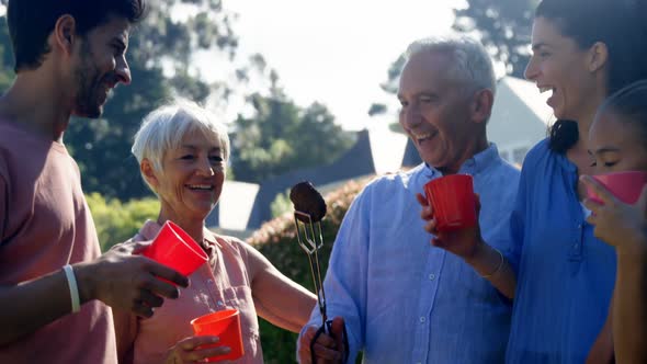 Family laughing and talking while preparing barbecue in the park