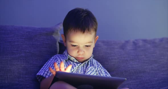 Cute Child Entertaining With Tablet. Little Boy Spending Leisure Time Playing Mobile Game