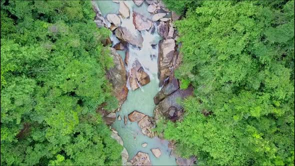 Drone Cam Approaches Close To Foamy Waterfall Among Stones
