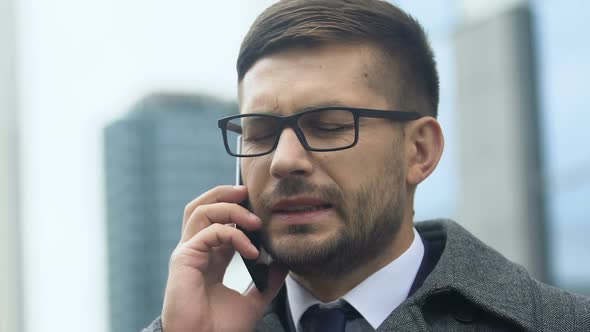 Young Businessman Talking Phone and Having Headache Outdoors, Stressful Life