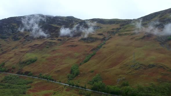 Cinematic pan of scottish highland road with misty mountain in background