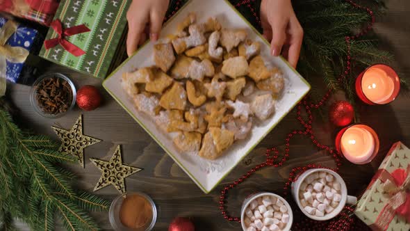 Hand Puts a Plate of Christmas Cookies on the Table