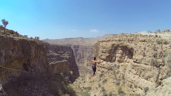 A man balances while tightrope walking and slacklining across a canyon