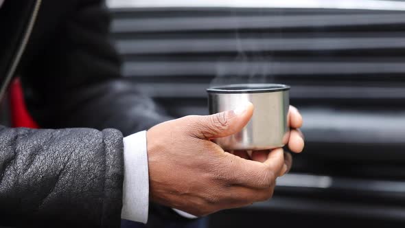 Man listening to music and holding a hot cup of coffee