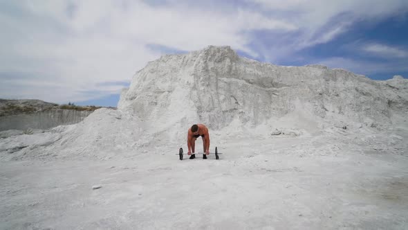 Strong shirtless athlete taking heavy barbell outdoors.