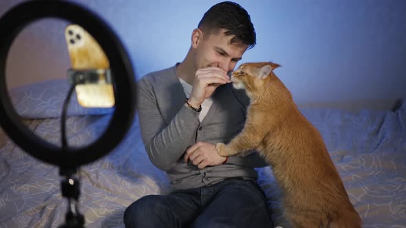 Smiling Male Blogger Live Streaming How He Playing and Feeding His Cat