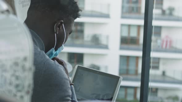 African American Black Man Working on the Laptop. Removing Face Mask To Drink Tea or Coffee. Office