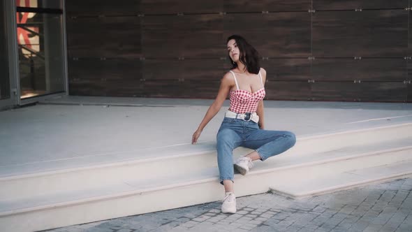 Young Slim Caucasian Brunette Woman Model in Casual Clothes Sits on the Steps