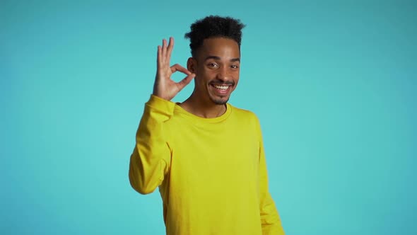 Young man making OK sign over blue background. Winner. Success. 