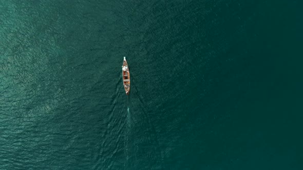 Aerial flight above young couple lyes down on long boat among bright turquoise sea and coral bay