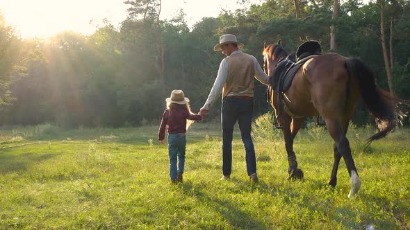 A Cowboy with a Horse and His Beautiful Daughter are Walking in the Pasture