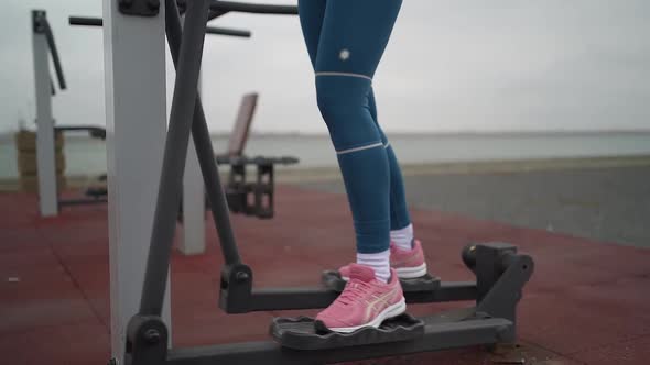 Portrait of woman in sportswear exercising on training apparatus on sports ground