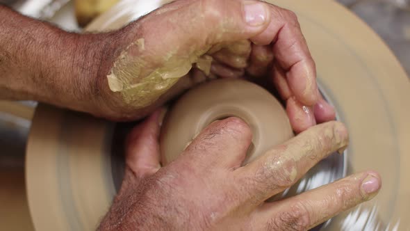 Potter's Hands Use Their Fingers to Shape Wet Clay Using Potter's Wheel