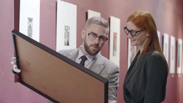 Male Art Expert Discussing Painting with Female Gallery Manager