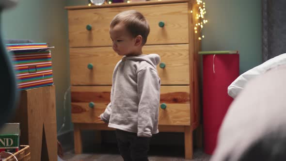 Little Asian boy in hoodie walking at home